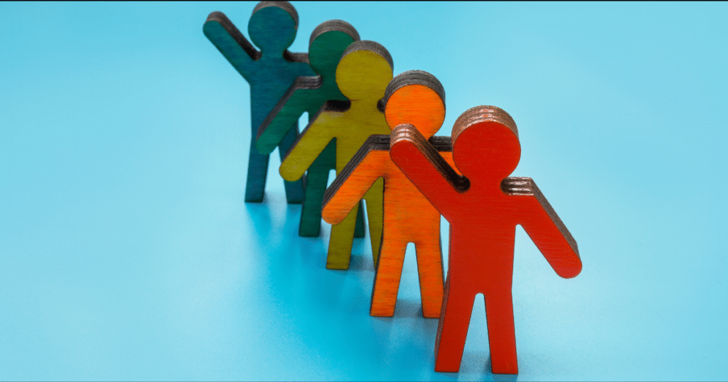 Colorful wooden figures standing in line waving.