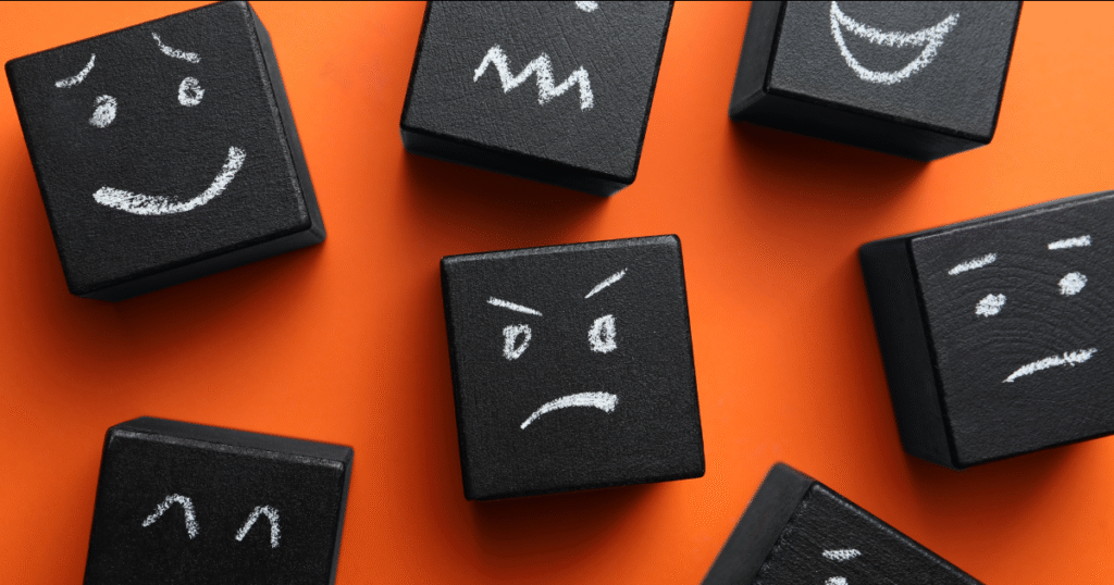 Black blocks with chalk-drawn faces on orange background.