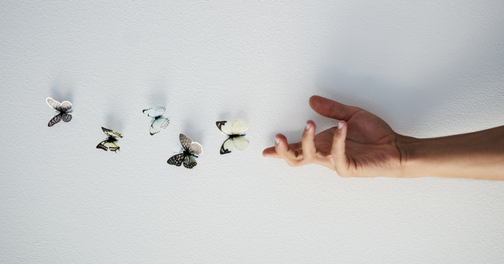 Hand releasing colorful butterflies indoors.